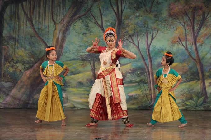 Lead dancer flanked by two child performers on stage